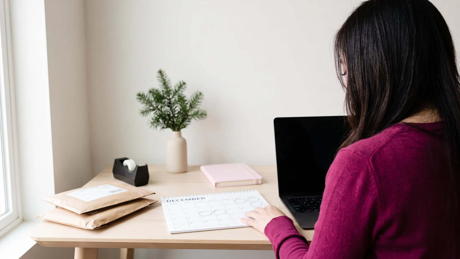 Shopify store owner at a December desk planning a holiday shipping deadlines page
