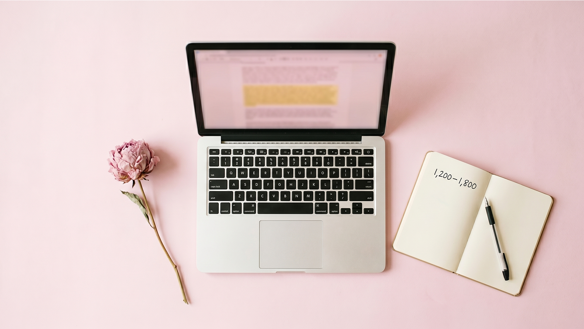 Open laptop with a Shopify blog post draft and a notebook noting target word count ranges