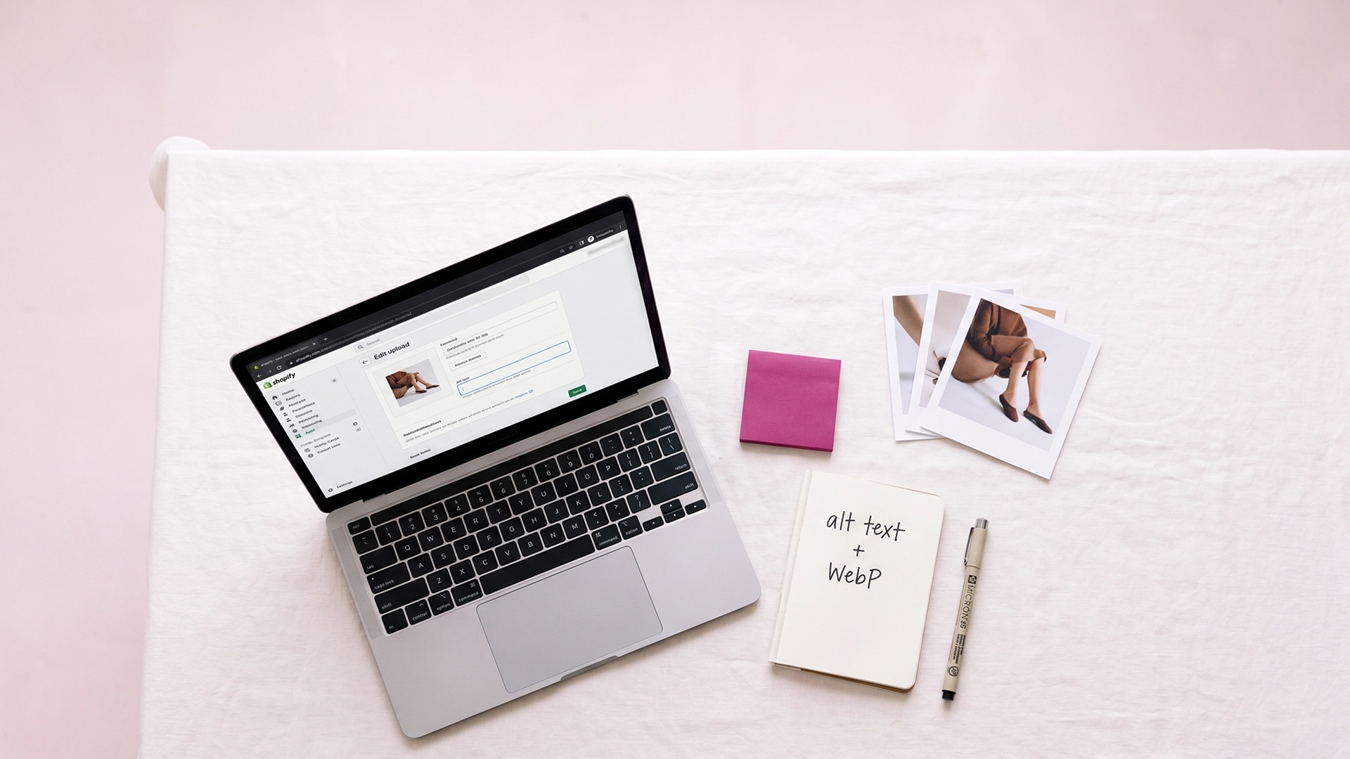 Clean editorial desk with a laptop showing a Shopify product upload screen and a handwritten note on image SEO